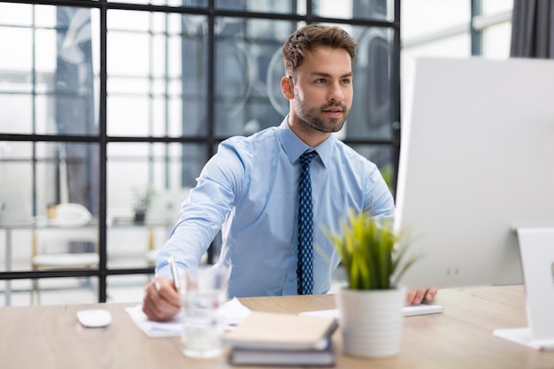 Young modern business man working using computer while sitting in the office