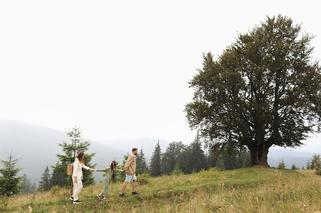 Young mom, dad with daughter travelling. parent playing and running with child outdoors, family trip in mountains.