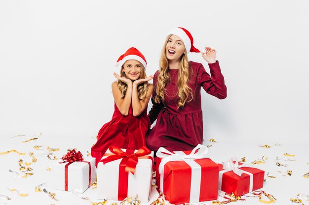 Young mom and daughter in Santa hats having fun with Christmas gifts