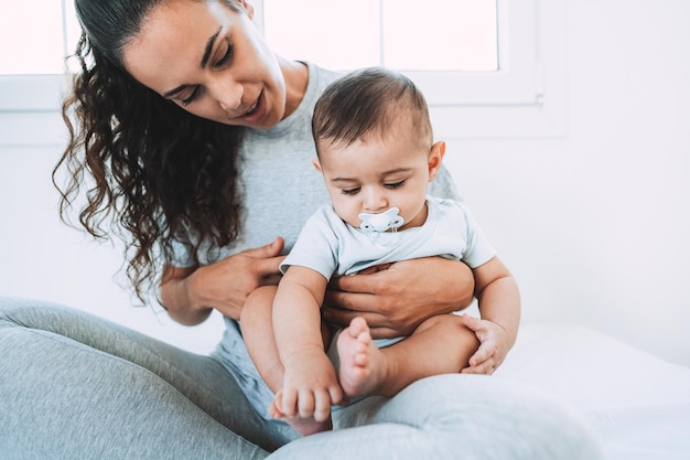 Young mom having fun with her son in bed at home - Focus on baby face