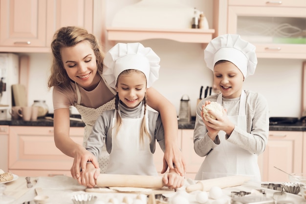 Young Mom Teaches Little Daughter to Roll a Dough.