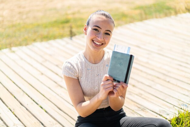 Young moroccan girl holding a passport at outdoors with happy expression