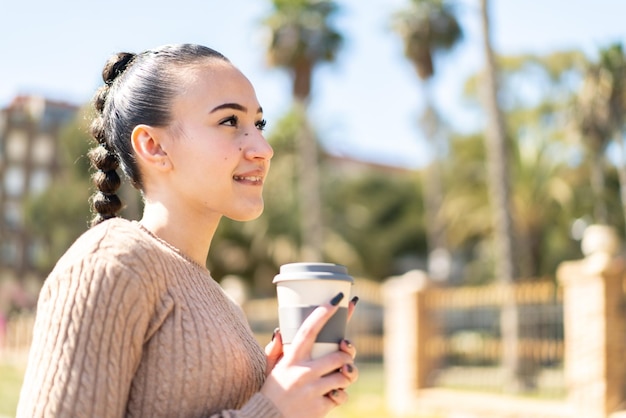 Young moroccan girl at outdoors holding a take away coffee and having doubts