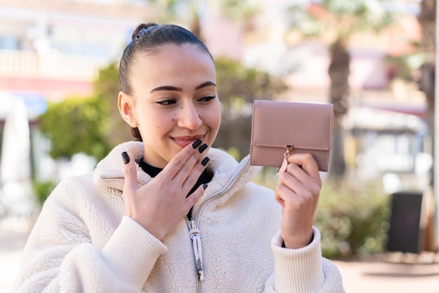 Young moroccan girl at outdoors holding a wallet and looking it