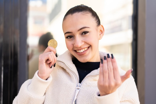 Young moroccan girl at outdoors inviting to come with hand Happy that you came