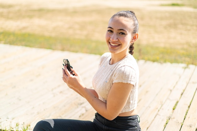 Young moroccan girl at outdoors sending a message or email with the mobile