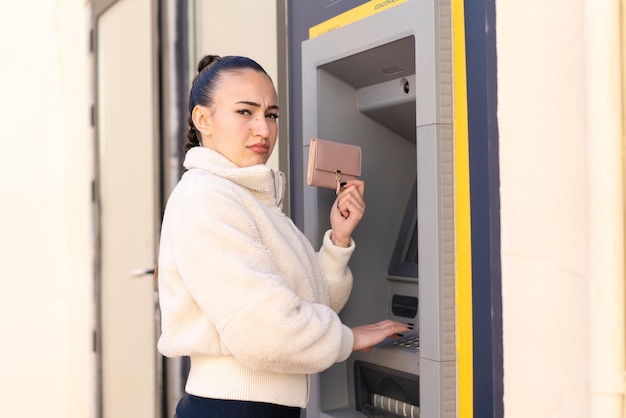 Young moroccan girl at outdoors using an ATM