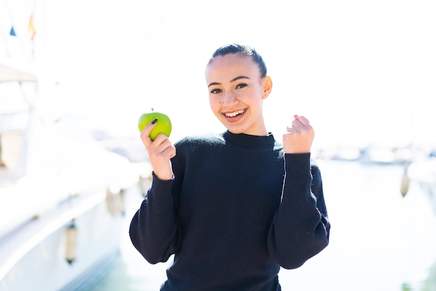 Young moroccan girl with an apple at outdoors celebrating a victory