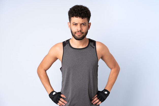 Young Moroccan man isolated on blue background posing with arms at hip