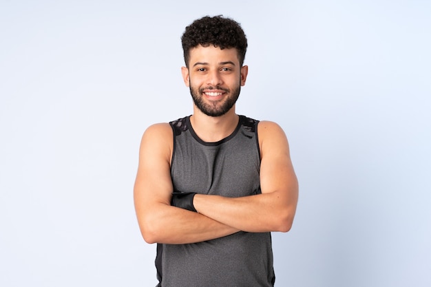 Young Moroccan man isolated on blue wall with arms crossed