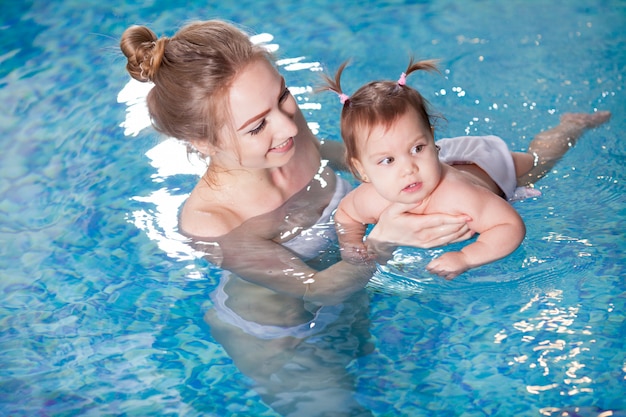 Young mother bathes the baby in the pool.