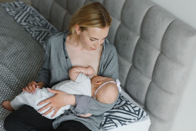 Young mother breastfeeding her newborn baby boy at home