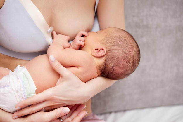 Young mother breastfeeding her newborn baby at home