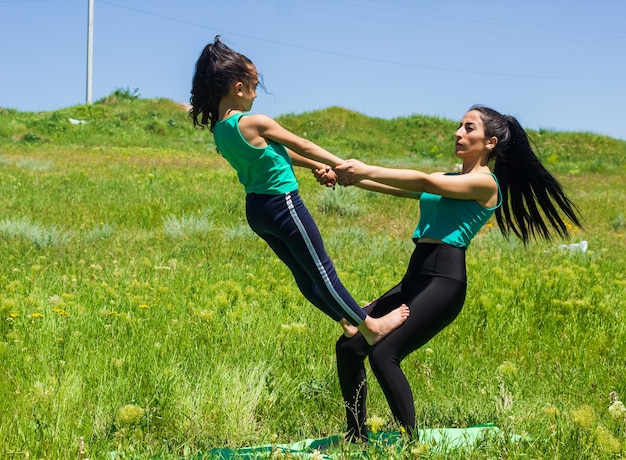 young mother and daughter doing yoga exercises young woman doing yoga exercises in the park