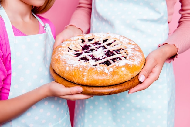 Young mother and daughter holding cake