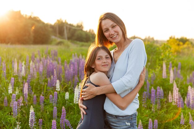 Young mother embracing her child outdoor woman and teenage girl on summer field with blooming wild f