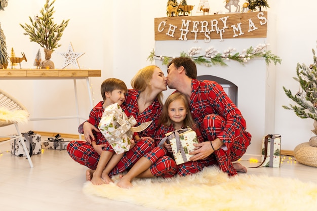 Young mother and father and two little children sitting by a fireplace