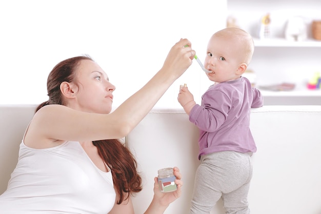 Young mother feeds the baby fruit puree