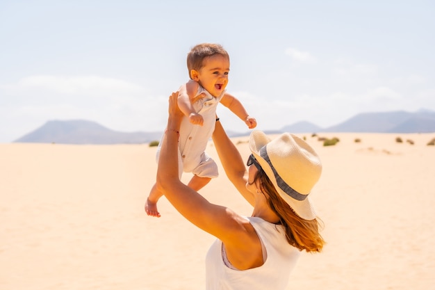 Young mother having fun with her son on vacation in the dunes of Corralejo Natural Park, Fuerteventura, Canary Islands. Spain