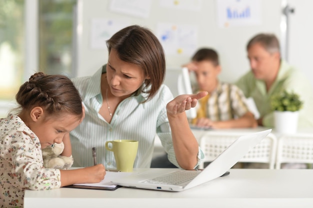 Young mother helping her cute little daughter doing homework