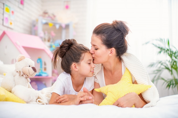 young mother and her daughter lying on the bed.