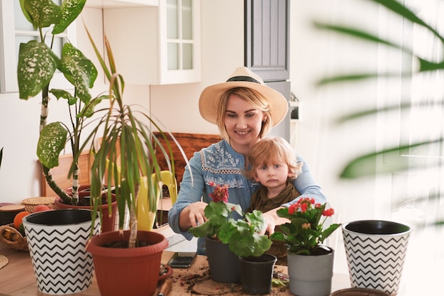 Young mother and her son are engaged in the cultivation of home flowers at home