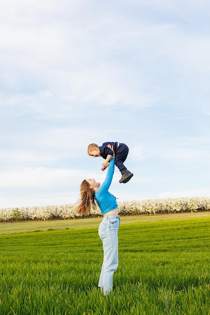 A young mother and her son are lying in the green grass Family relations of mother and child A happy family