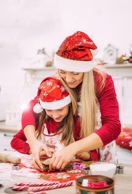 A young mother and her teenage daughter are standing in the kitchen