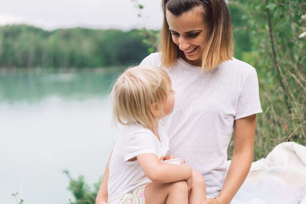 Young mother holding her baby. Mother and little daughter having good time in the nature. 