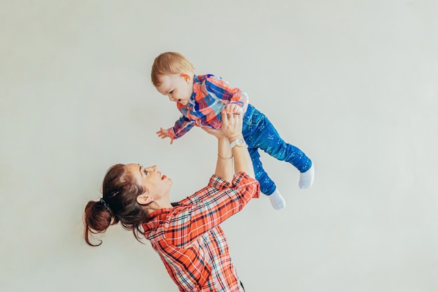 Young mother holding her newborn child. Woman and infant little baby playing isolated white wall. Happy mom of breast feeding baby. Family maternity tenderness parenthood responsibility concept.