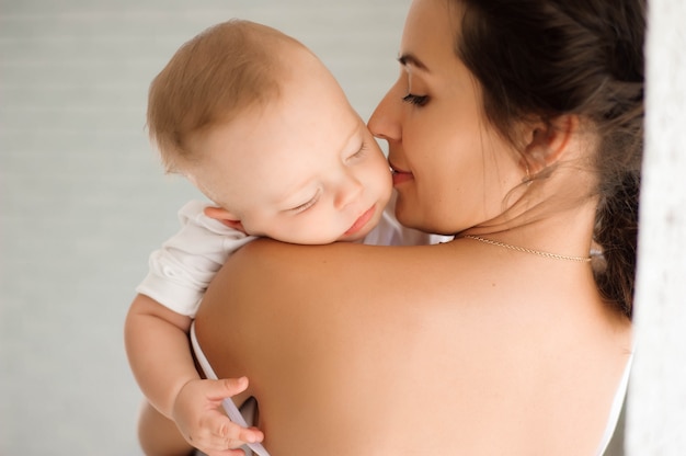 Young mother, holding tenderly her newborn baby boy