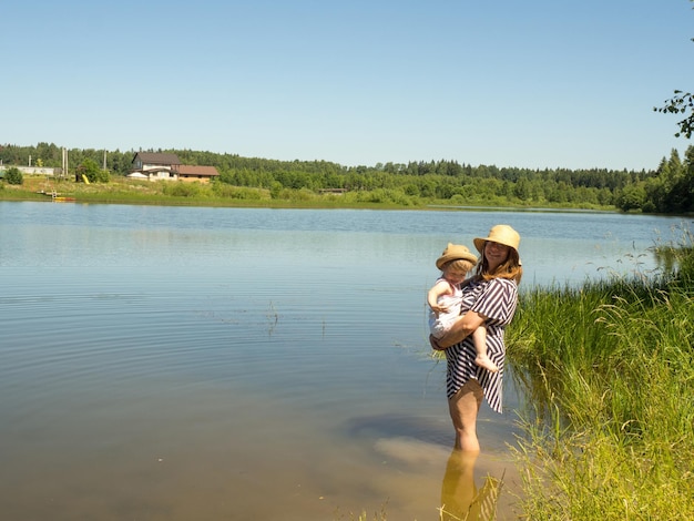 A young mother holds her little daughter in her arms while swimming