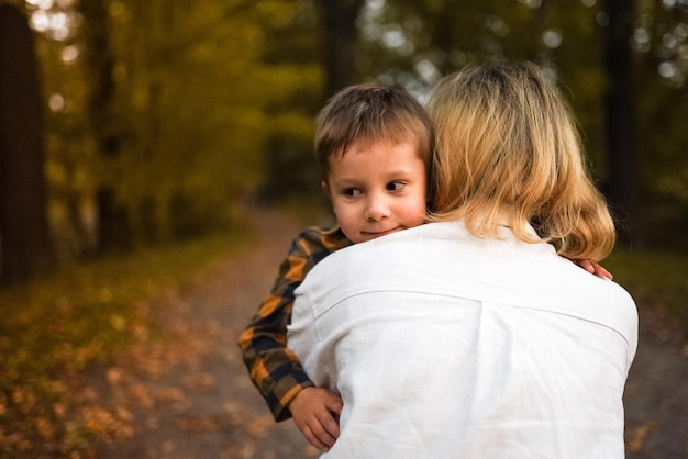 Young mother hugging her little son in autumn park