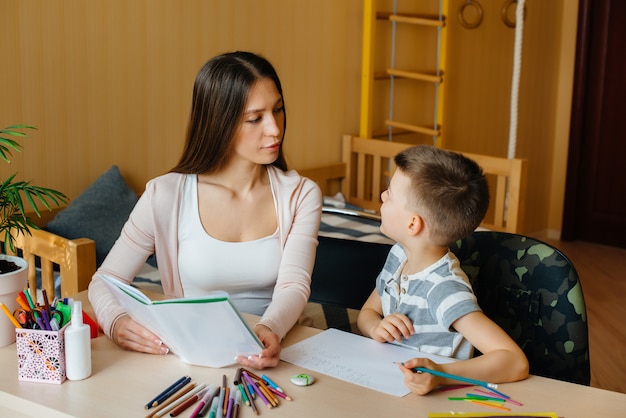 A young mother is doing homework with her son at home