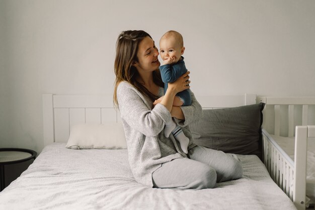 A young mother is play with little baby boy. Mother of a nursing baby. Happy motherhood. The family is at home. Portrait of a happy mother and child.