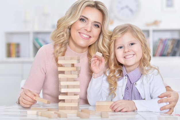 Young mother and little daughter playing with wooden blocks