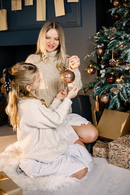 Young mother and little girl decorating christmas tree at home