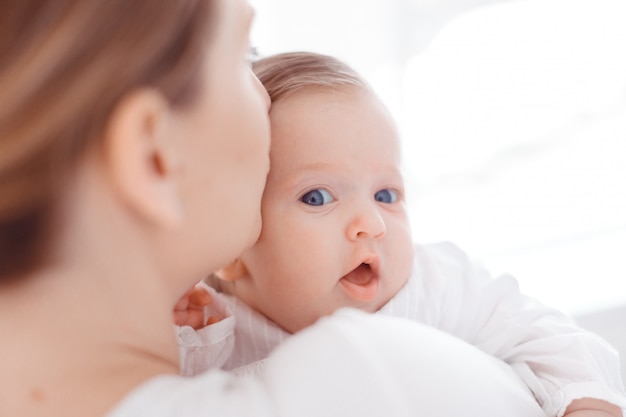 Young mother and newborn baby in white bedroom