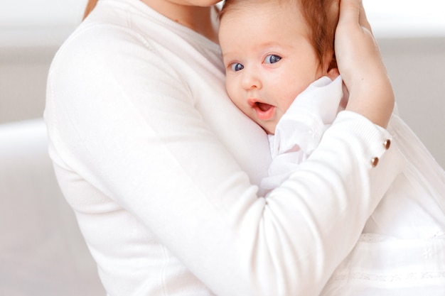 Young mother and newborn baby in white bedroom