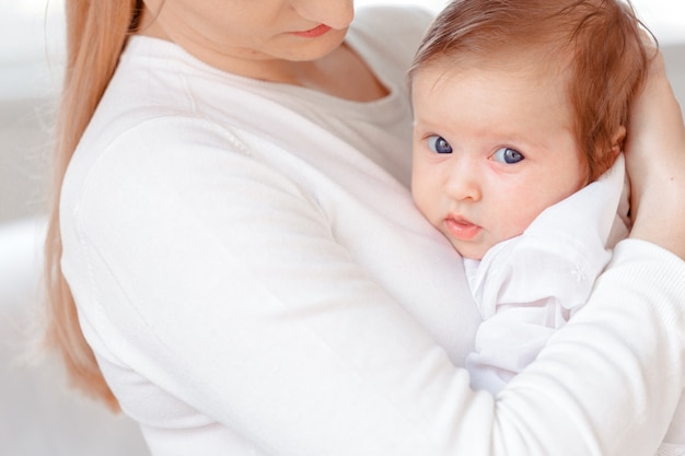 Young mother and newborn baby in white bedroom