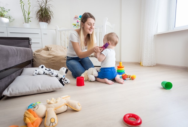 Young mother playing her baby son and pretending talking by phone