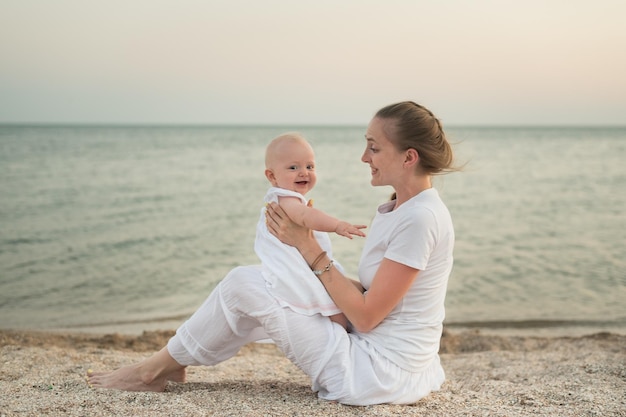 Young mother playing with baby on beach Vacation with young children at sea