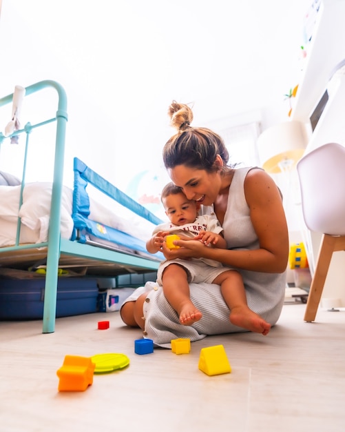 Young mother playing with her child in the room with toys