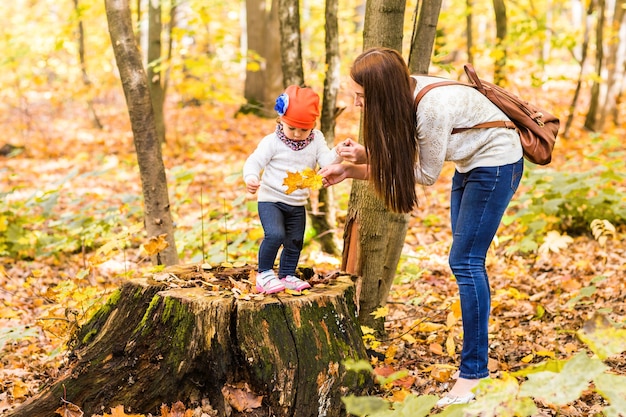 Young mother playing with her daughter in autumn park.