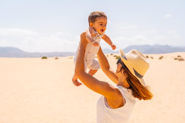 Young mother playing with her son on vacation in the dunes of Corralejo Natural Park