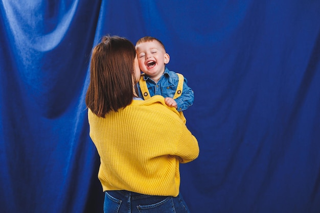 A young mother plays with her child on a blue background Family relationship with the child Raising a child playing with a child