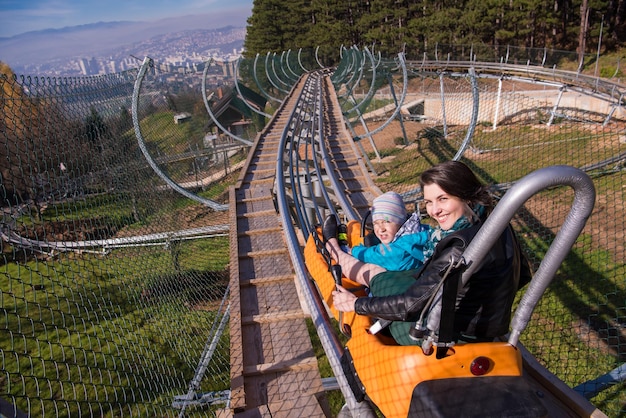 Photo young mother and son driving alpine coaster