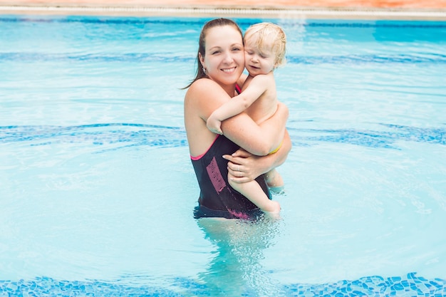 Young mother teach her little son, how to swim in a swimming pool