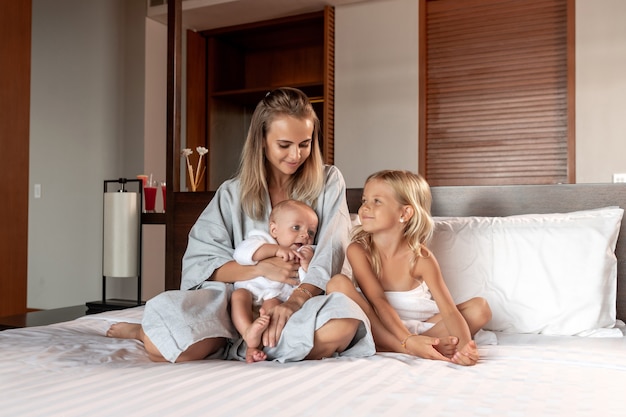 A young mother and two children are sitting in bed