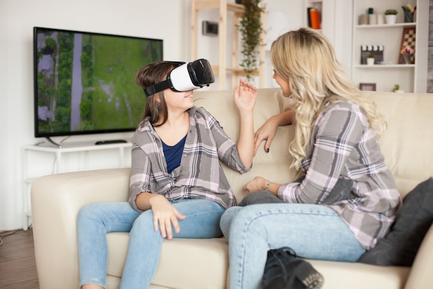 Young mother using modern gadgets for her little girl education. Virtual reality glasses.